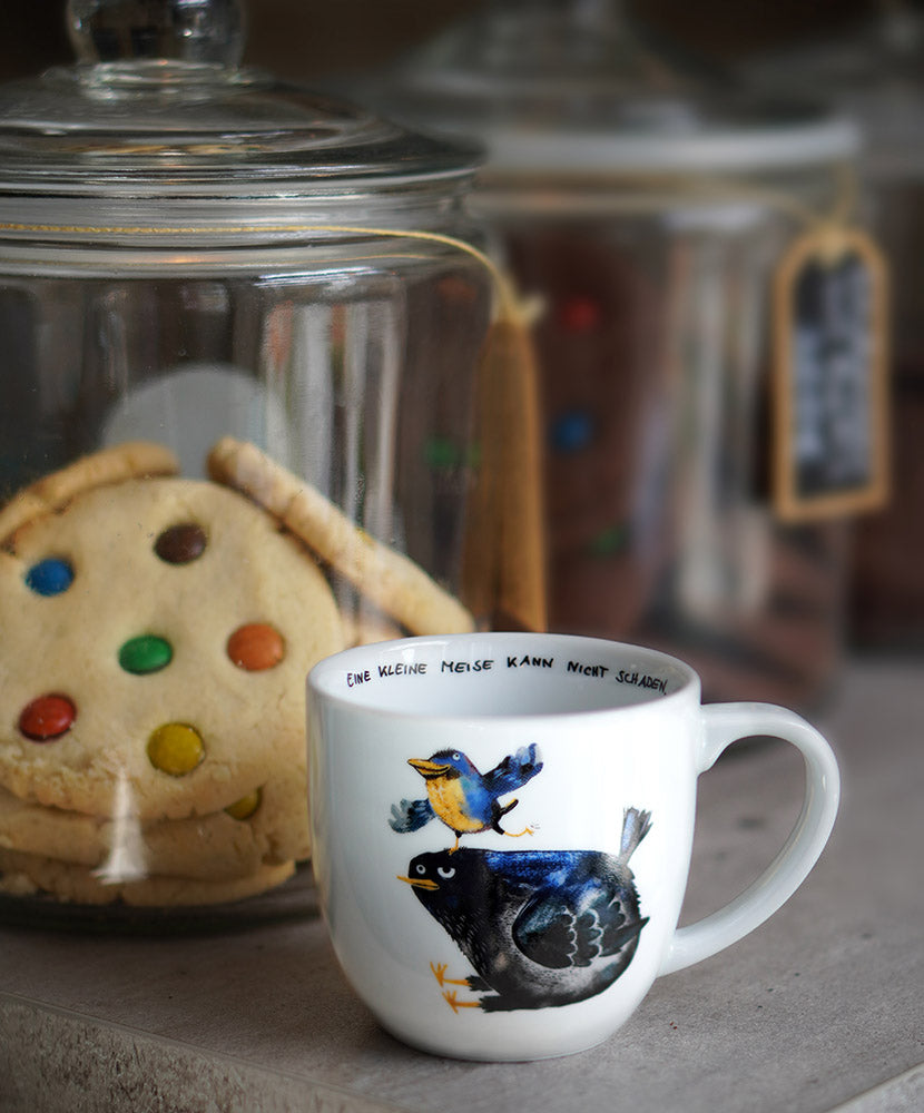 Tasse mit einer Amsel drauf mit einer Meise auf dem Kopf und dem Spruch "Eine kleine Meise kann nicht schaden.".